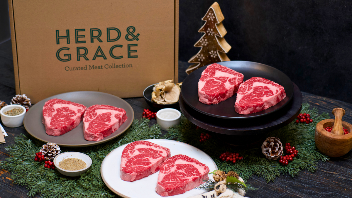Raw meat steaks on plates with 'Herd & Grace' packaging in the background.