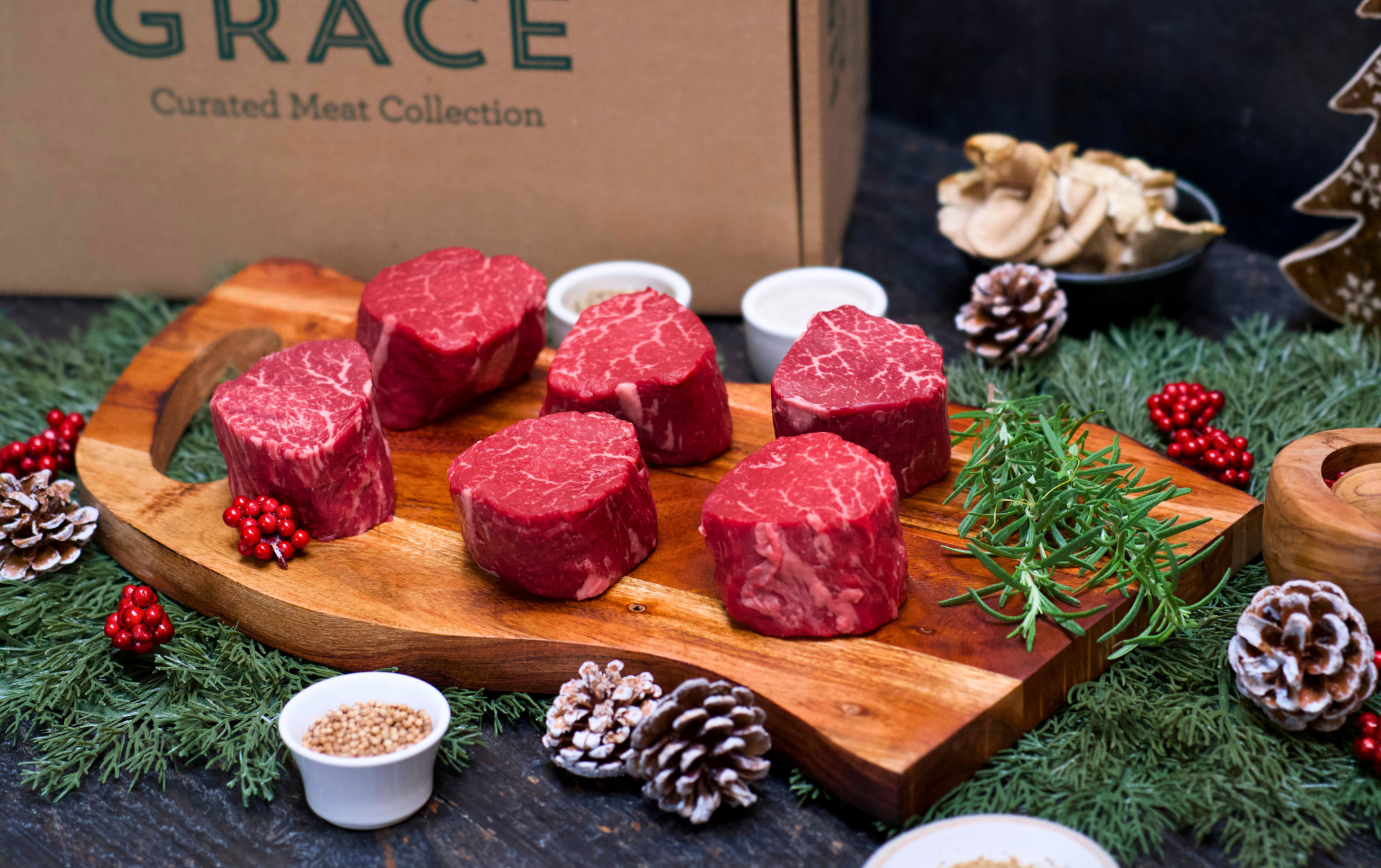 Raw meat steaks on a wooden board with decorative elements and 'Grace' 