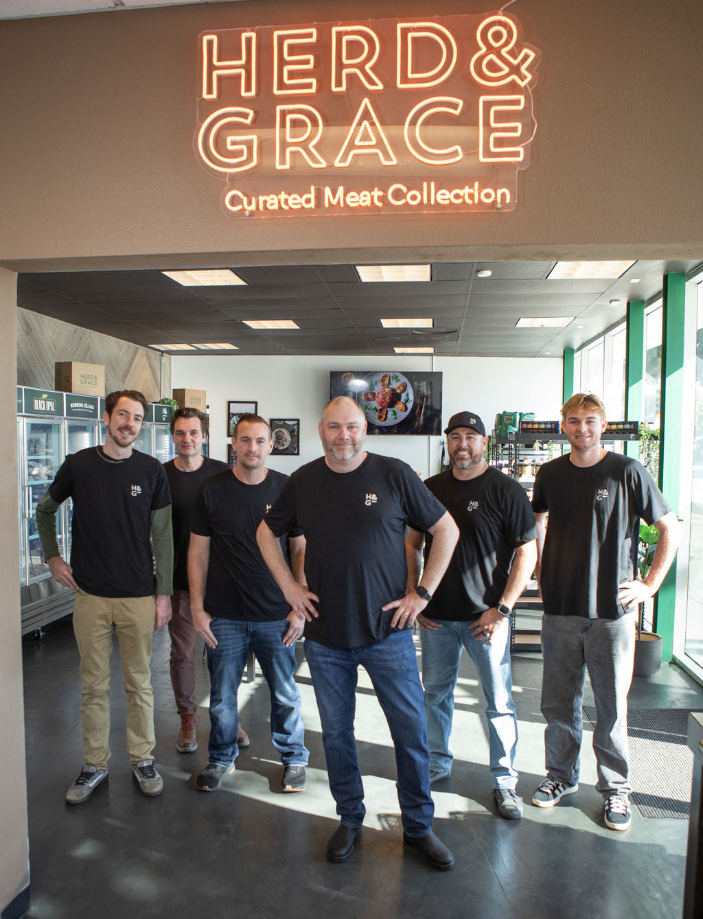 Herd & Grace team standing inside the store underneath the neon sign