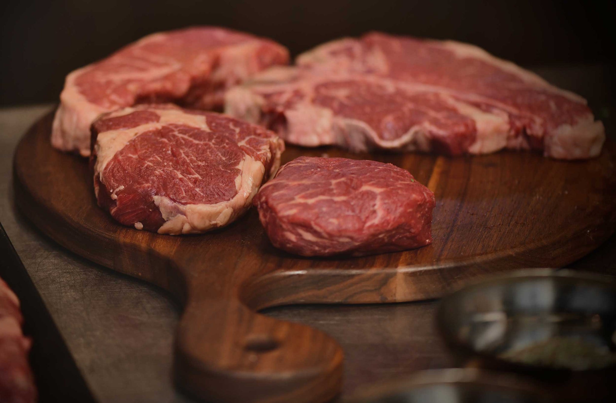 Herd & Grace raw marbled beef steaks on a wooden cutting board