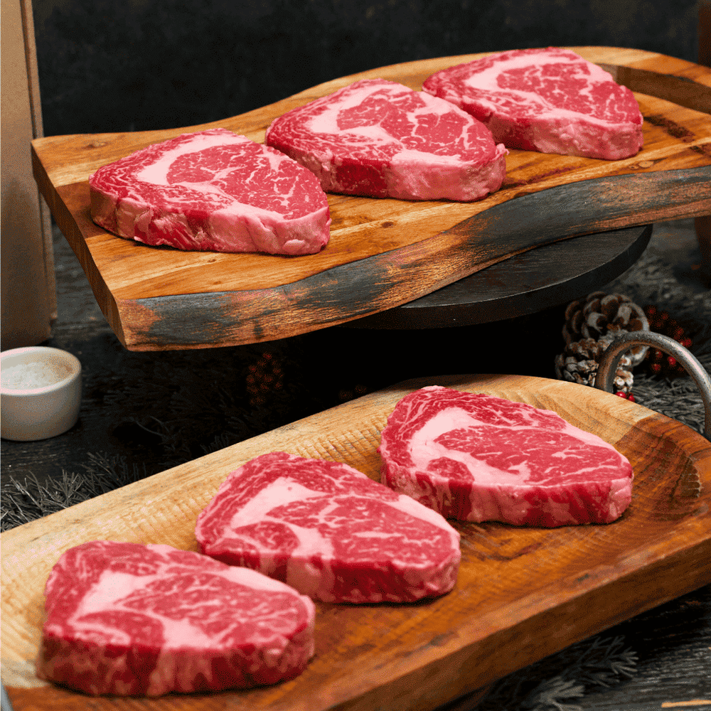 Holiday Sampler Pack 2PC Per Farm ribeye steaks on wood boards, marbled